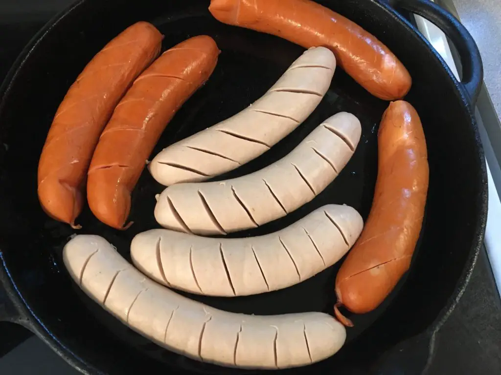 sausages for currywurst in a cast iron skillet