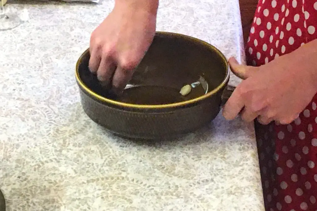 rubbing garlic around a fondue pot