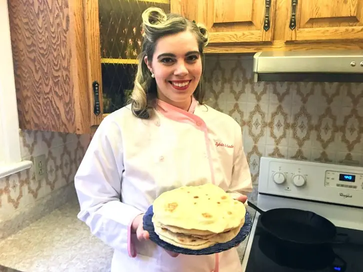 holding a plate of sesame naan bread