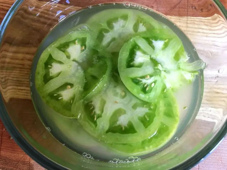 green tomatoes marinating in pickle juice